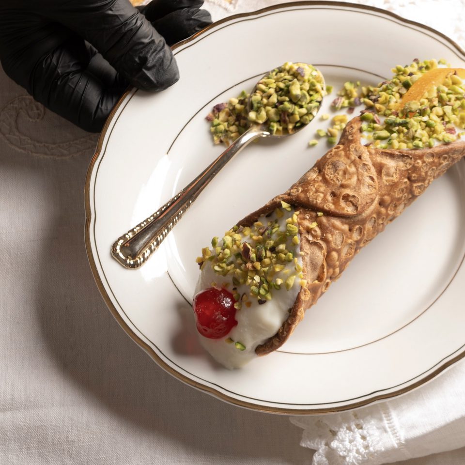Due cannoli siciliani farciti, decorati con pistacchio e ciliegia candita
