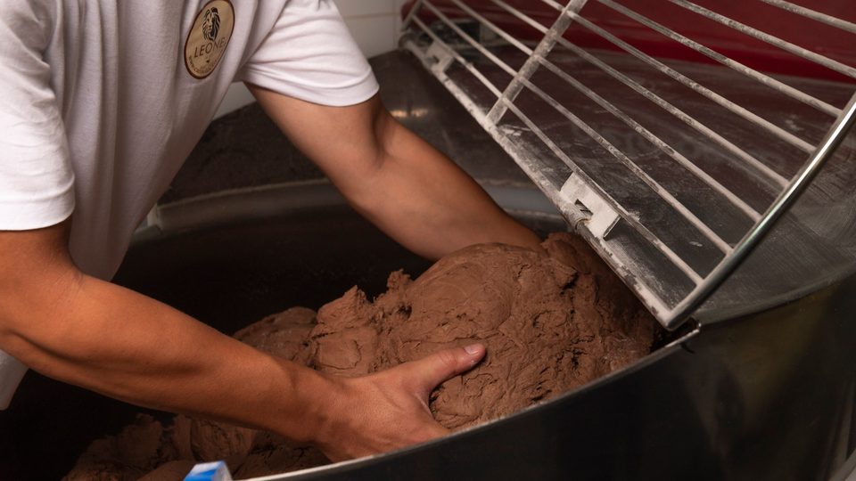 Mani che lavorano l'impasto per le scorze di cannolo in un'impastatrice