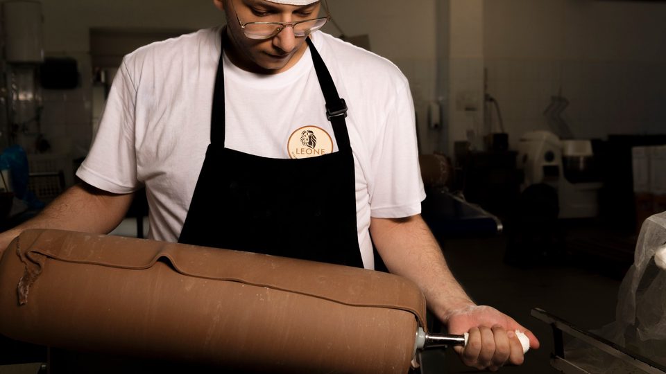 Sfogliatura dell'impasto con la macchina a rulli nel laboratorio Leone
